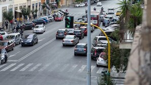 Un carrer urbà animat amb edificis d'altures diverses, cotxes aparcats i un pas de vianants.