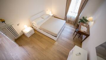 A modern hotel room with a bed, bedside lamps, a small table with a map, and a radiator.