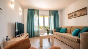 A living room with a TV, sofa, and coffee table. - 2 Bedroom Apartment- Ona Aucanada Alcudia, Mallorca (Aucanada, Puerto de Alcudia, Illes Balears)
