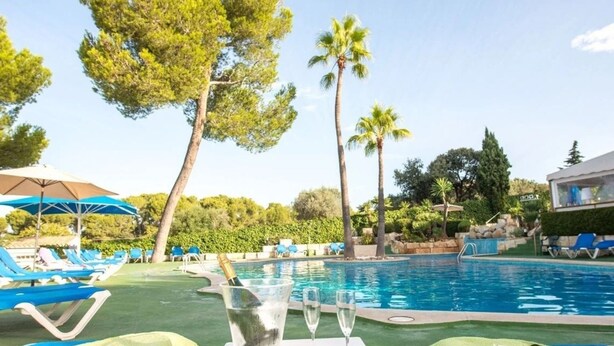 A poolside area with lounge chairs, a table with a bottle and glasses, and a clear view of the pool. - 2 Bedroom Apartment- Ona Aucanada Alcudia, Mallorca (Aucanada, Puerto de Alcudia, Illes Balears)