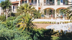 A Mediterranean-style building with multiple balconies, a courtyard with outdoor seating, and lush greenery. - 2 Bedroom Apartment- Ona Aucanada Alcudia, Mallorca (Aucanada, Puerto de Alcudia, Illes Balears)