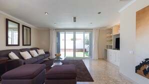 A modern living room with a sofa set, a coffee table, and a large window with curtains. - Private pool and spectacular barbecue area (San Bartolomé de Tirajana)