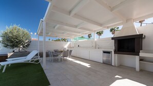 An outdoor kitchen area with a grill, dining table, and chairs. - Private pool and spectacular barbecue area (San Bartolomé de Tirajana)