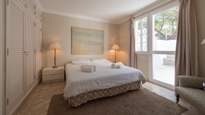 A bedroom with a large bed, two bedside lamps, a nightstand, a window with curtains, and a view of the outdoors. - Private pool and spectacular barbecue area (San Bartolomé de Tirajana)