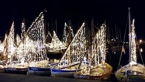 Ein Yachthafen bei Nacht mit angestaubten Booten, verziert mit Lichterketten.