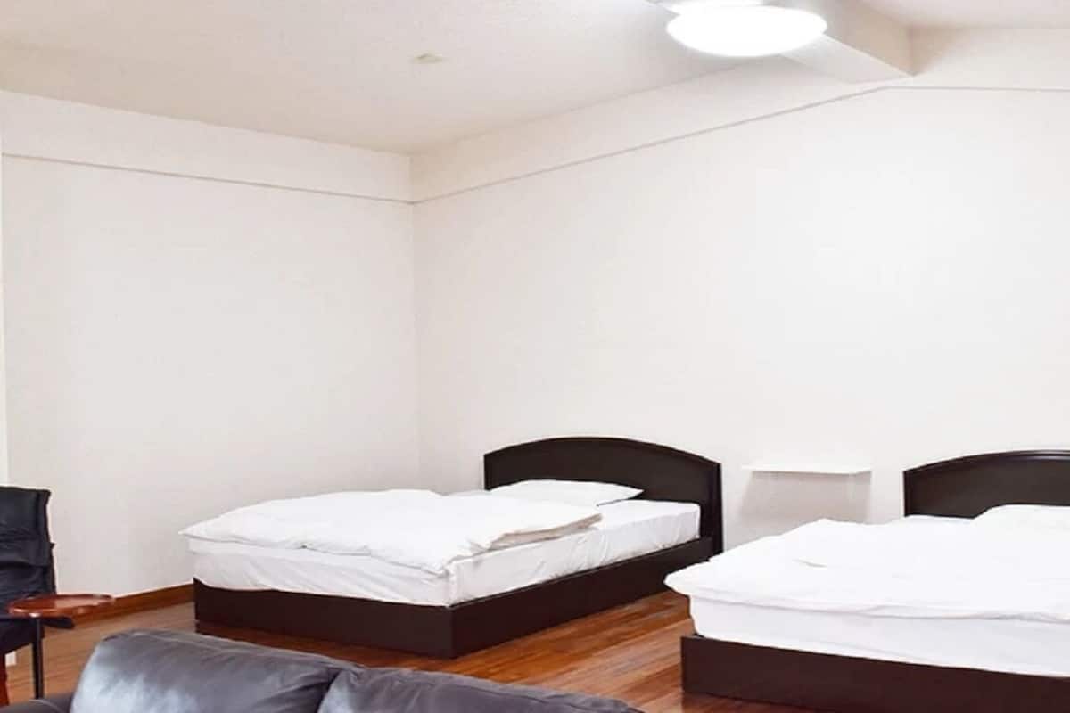 A room with two beds, a chair, and a small table.