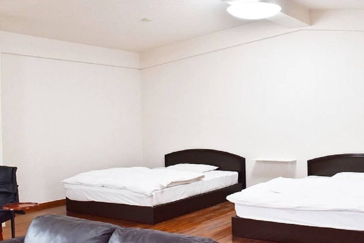 A room with two beds, a chair, and a small table.