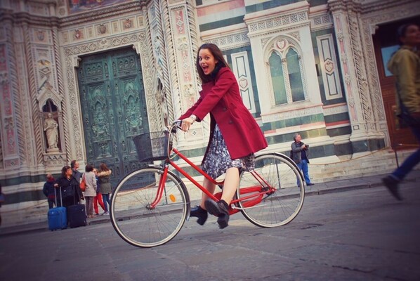 Une personne à vélo devant un bâtiment dont l’architecture est richement décorée.