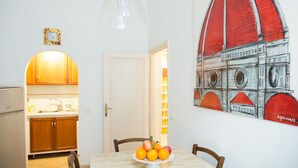 A dining area with a table set for two, a fruit bowl, and a wall with a red and white architectural mural. - APPARTAMENT IN THE CITY CENTER OF FLORENCE (Firenze)