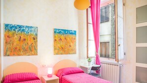 A bedroom with two beds, a desk, and a window with pink curtains. - APPARTAMENT IN THE CITY CENTER OF FLORENCE (Firenze)