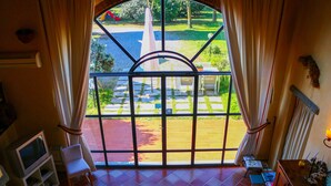 Una habitación con un ventanal grande, televisor, una silla y una mesita.