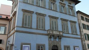 Un edificio de varios pisos con un estilo arquitectónico clásico, con ventanas simétricas y una entrada central con arco.