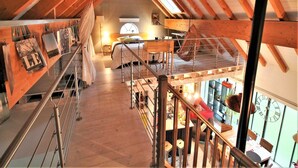 Um quarto espaçoso no estilo loft, com pé-direito alto, escada de madeira e vista para a cidade.