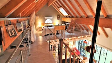 Ein geräumiges Schlafzimmer im Loft-Stil mit hohen Decken, einer Holztreppe und Blick auf die Stadt.
