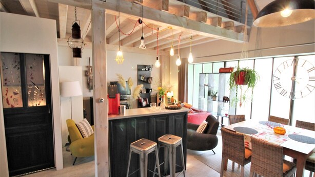 Cozinha moderna com ilha central, banquetas e iluminação pendente.