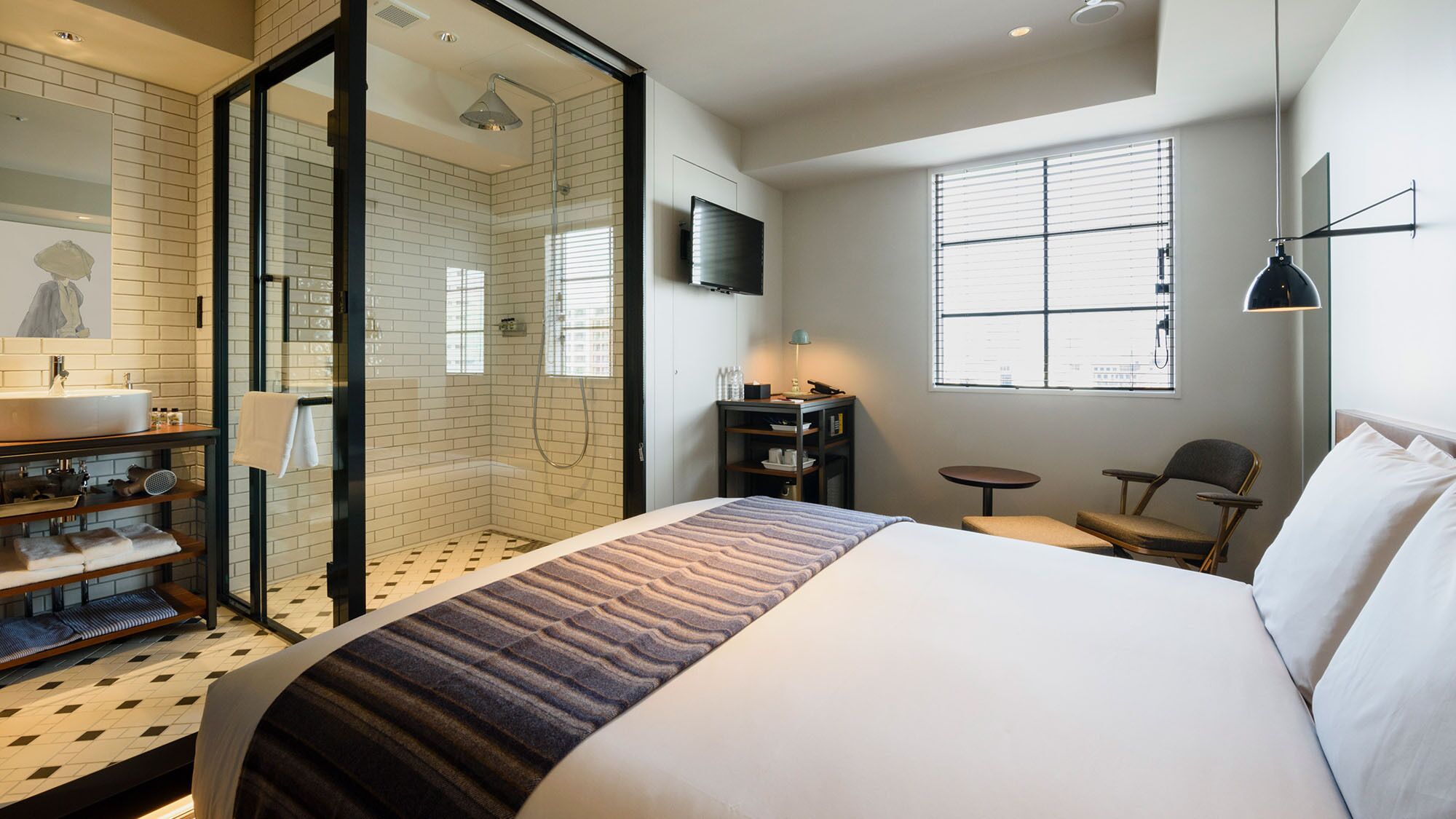 Une chambre d’hôtel avec un grand lit, une douche, une télévision, une petite table et une chaise.