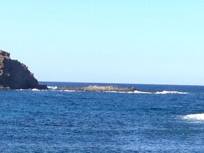 A coastal scene with a rocky outcrop and calm sea.