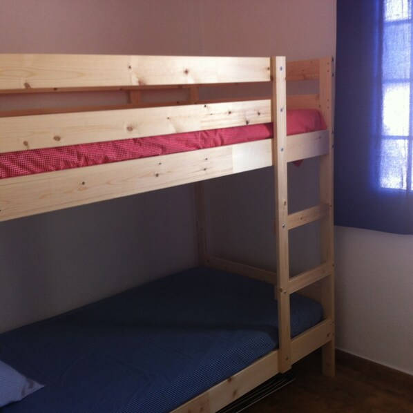 A bunk bed with a wooden frame and a blue mattress.