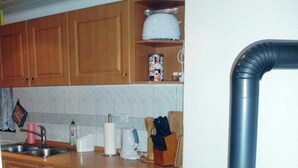 Une cuisine avec des meubles de rangement en bois, un évier, une cuisinière et une poubelle.