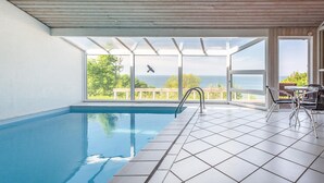 An indoor swimming pool with a view of the sea, a wooden ceiling, and a tiled floor. - 4 bedroom beautiful home in Asnæs (Asnæs)