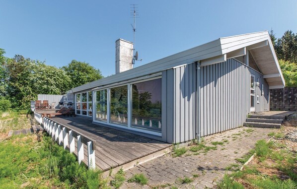 A modern house with a deck, large sliding glass doors, and a chimney. - 4 bedroom beautiful home in Asnæs (Asnæs)