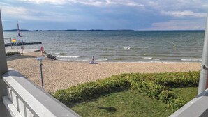 A beach with a rocky shoreline, a flag, and a pier in the background. - Cozy apartment in Rechlin (Rechlin)