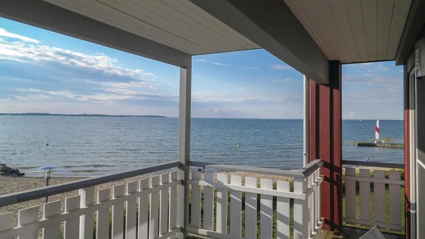 A covered balcony with a view of the sea and a distant shoreline. - Cozy apartment in Rechlin (Rechlin)