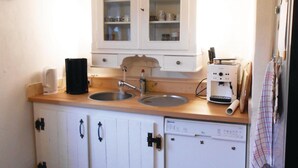 Una piccola cucina con due lavandini, una macchina da caffè e una lavastoviglie.