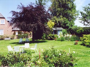 A garden with a small shed, a brick building, and outdoor seating.