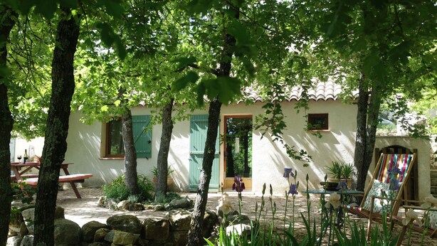 A courtyard with a stone wall, a wooden bench, a picnic table, and a colorful chair. - Nice cottage in the Luberon Regional Park (Viens)