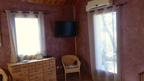 A room with a wooden dresser, a wicker chair, a flat-screen TV, and two windows with curtains. - Nice cottage in the Luberon Regional Park (Viens)