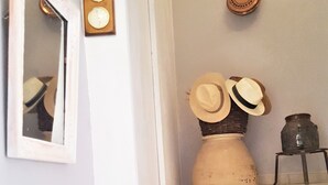 Una escalera con un jarrón de flores secas y sombreros en la plataforma.