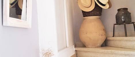 A staircase with a vase of dried flowers and hats on the landing.