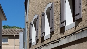 Un edificio con varias ventanas, algunas con contraventanas, y una señal de no estacionamiento a la vista.