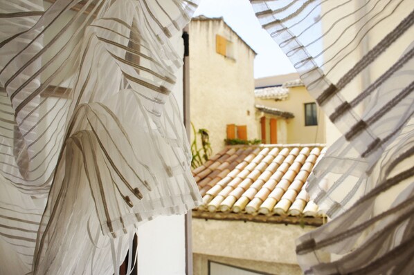A view through sheer curtains of a building with a tiled roof and a door with a small window.