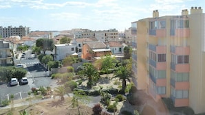 A residential area with a mix of single and multi-story buildings, a parking lot, and a small garden area with palm trees. - Family-Friendly 3-Room Apartment with A/C, WiFi, and Garage, 250m from Beach in Le Grau-du-Roi (Le Grau-du-Roi)