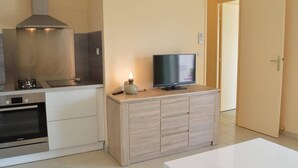 A modern kitchen with a Bosch oven, a stove, and a TV on a wooden cabinet. - Family-Friendly 3-Room Apartment with A/C, WiFi, and Garage, 250m from Beach in Le Grau-du-Roi (Le Grau-du-Roi)