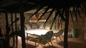 A cozy, dimly lit outdoor seating area with a thatched ceiling, a cushioned bench, and wicker chairs. - Casbah d'architecte,Chic et Luxe, 305 comments 5*,Optional meals and massages (Essaouira)