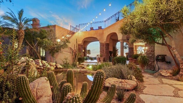 Un jardín desértico con cactus, un estanque y un puente de piedra.