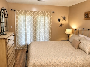 A bedroom with a bed, a dresser, a lamp, and decorative star wall art.