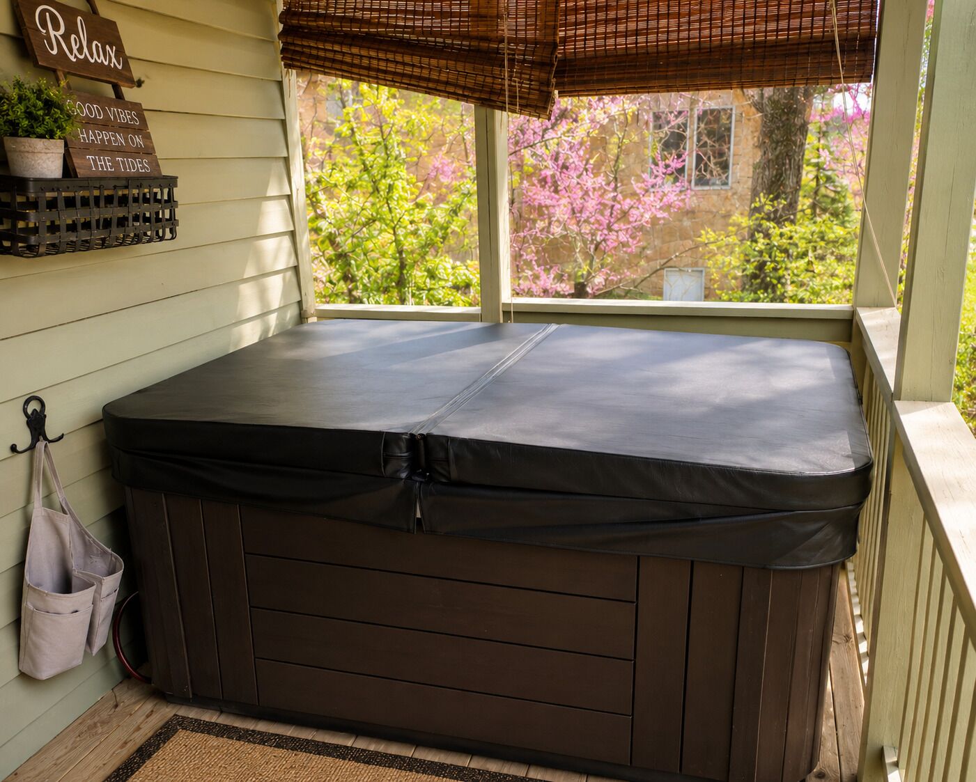 A hot tub in a covered porch area with a view of trees and a building.