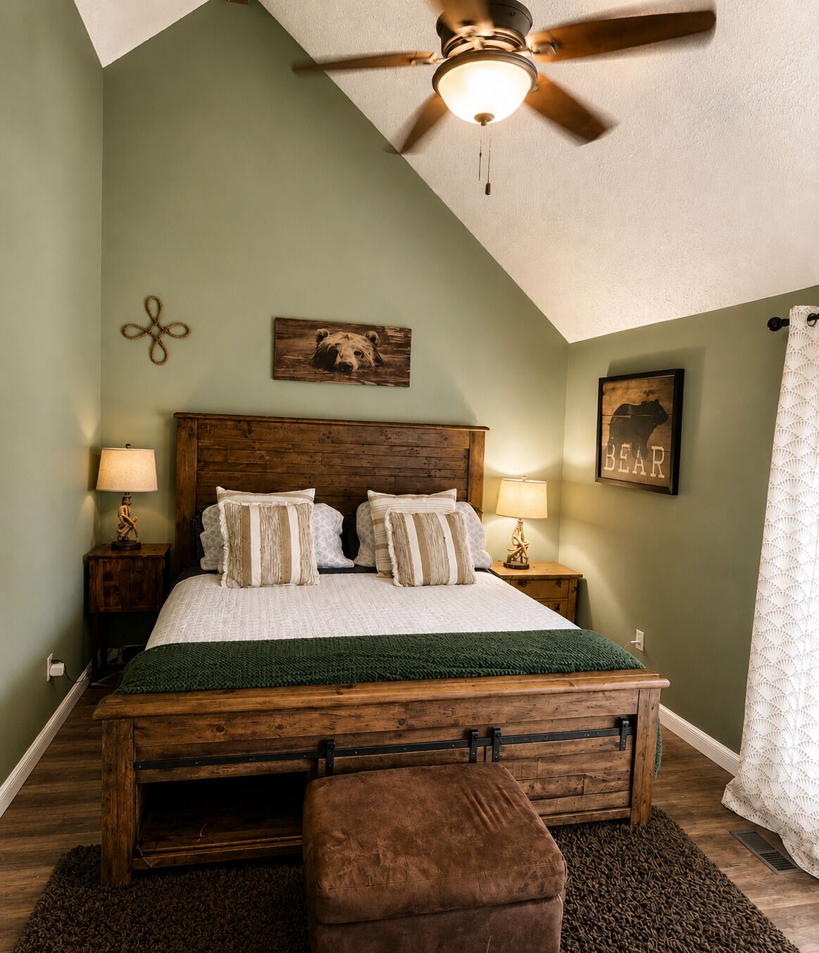 A bedroom with a wooden bed, two bedside tables, a ceiling fan, and a green rug.