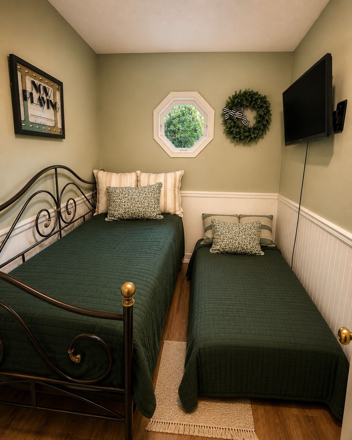 A bedroom with two beds, a window, a television, and a framed picture on the wall.