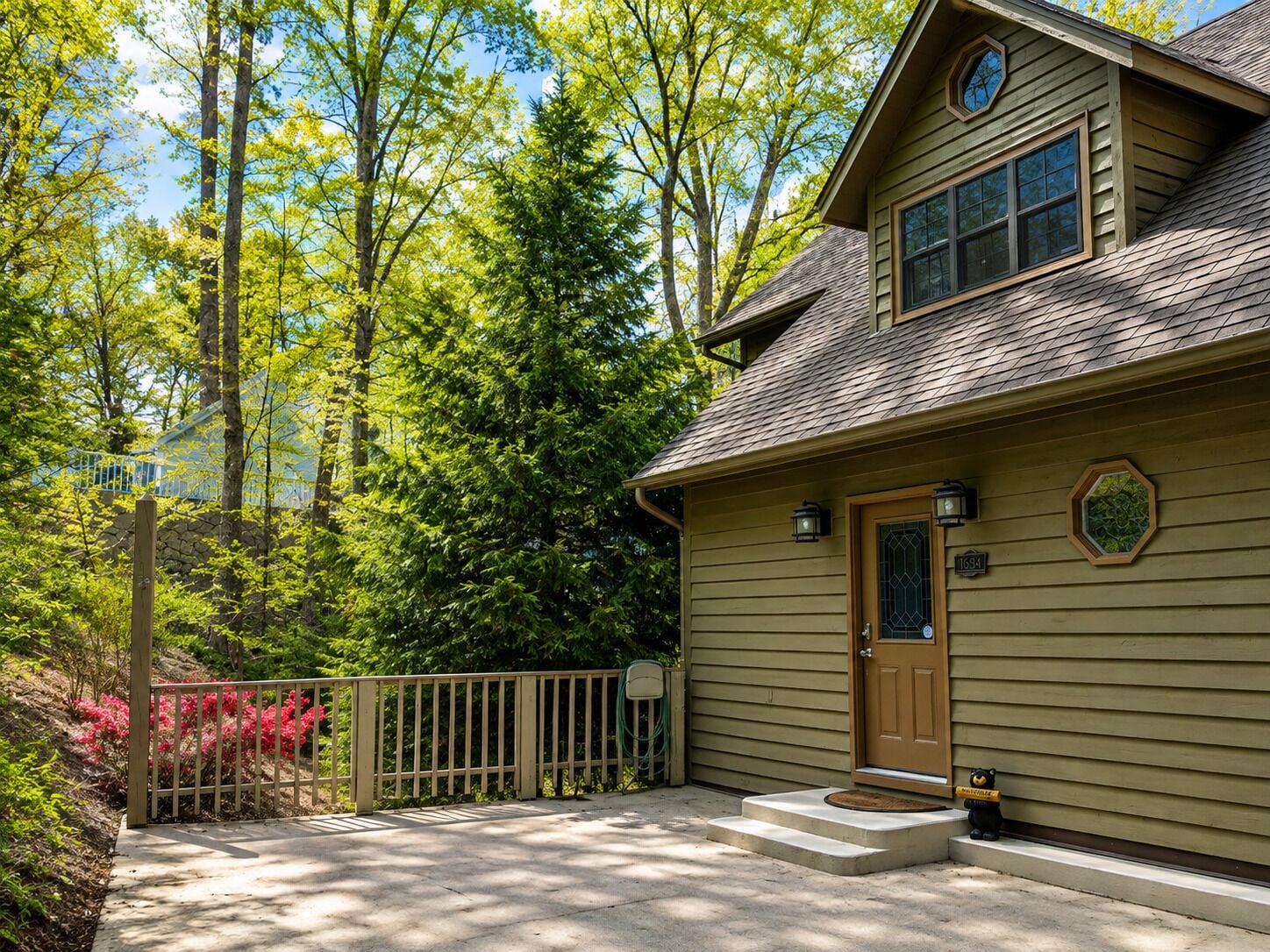 Une maison à deux étages avec un porche à l’avant, une clôture en bois et une boîte aux lettres.
