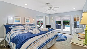 A bedroom with a bed, a ceiling fan, a desk with a lamp, and a view of the outdoors. -  VACAY TIME:HHI Retreat: Pool/Hot Tub/Near Beach, Pets, Last Minute Rentals Now! (Hilton Head Island)
