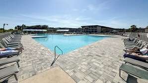 Ein Schwimmbecken mit Liegestühlen und einem Gebäude im Hintergrund.