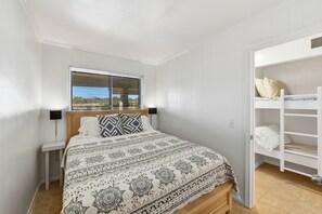 Une chambre à coucher comprenant un lit, une table de chevet, une fenêtre et une armoire intégrée.