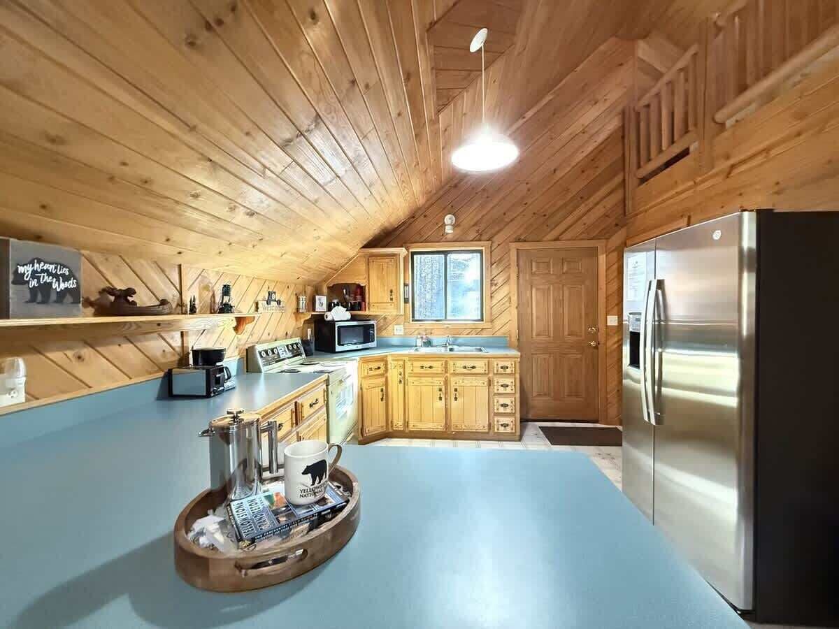 Eine Küche mit Holzausstattung, einem Edelstahlkühlschrank und einer blauen Arbeitsplatte.
