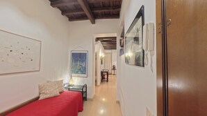 Un pasillo estrecho con una cama a la izquierda, una mesa con una lámpara y una puerta a la derecha.