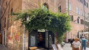 Un café con terraza, un menú en pizarra y fachada de un edificio de piedra rústica.